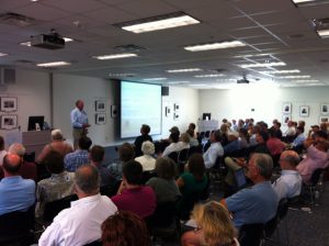 a man standing presenting information to a seated audience