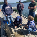 five people on a dock looking at nursery equipment