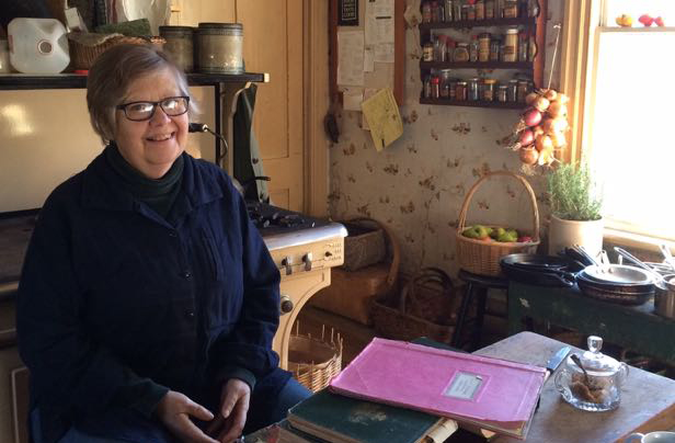Photo of Sandra Oliver in the kitchen with her books