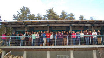 Dozens of conference participants line up for an outside photo