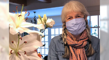 Esperanza Stancioff, masked, stands with a bouquet