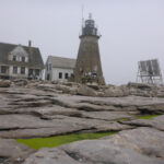 Lighthouse keepers house and Mount Desert Rock Light Tower, view from the northwest. Granite ledge, Foggy background.
