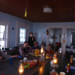 Evening time, people sitting around table with food. Lanterns.