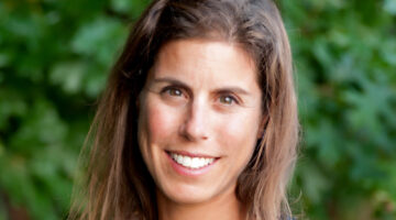 Woman looking at camera and smiling with green foliage in the background