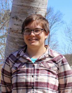 Eleanor Gnam standing in front of a birch tree with blue sky in the background