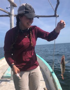 Katie Culp in a boat holding a fish water in the background