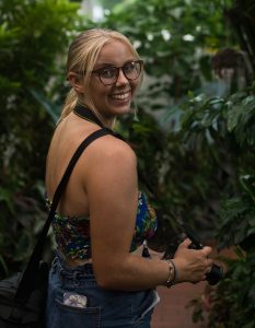 Rachael Smith surrounded by trees holding a camera