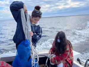 two young people coiling rope in a boat on the water