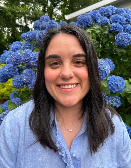 headshot of jerelle jesse in a blue button-down shirt in front of blue hydrangea bush