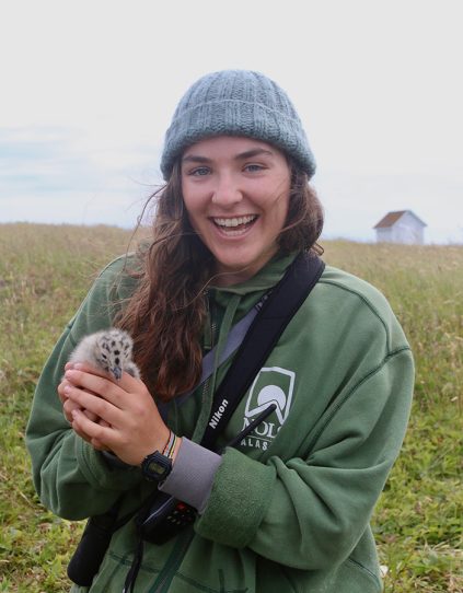 Lydia Burnet standing in a field holding a fledgling