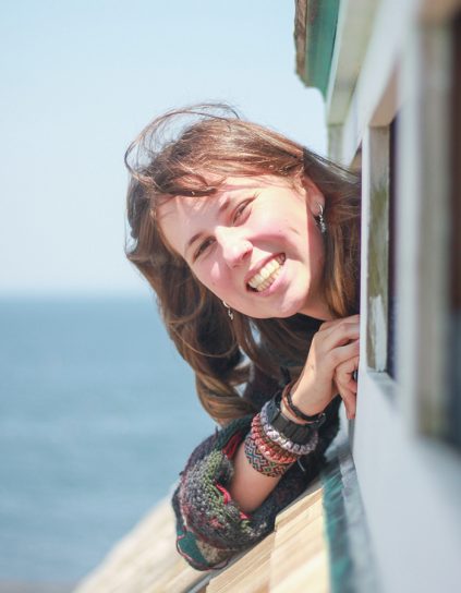 Megan Maloney leaning out of a window with the water behind