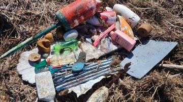 A gathered pile of marine debris, large pieces of plastic including buoys and other trash