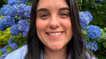 Jerelle Jesse smiles for the camera with blue hydrangeas in the background.
