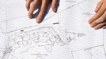 Hands layng on top of a blueprint layout.