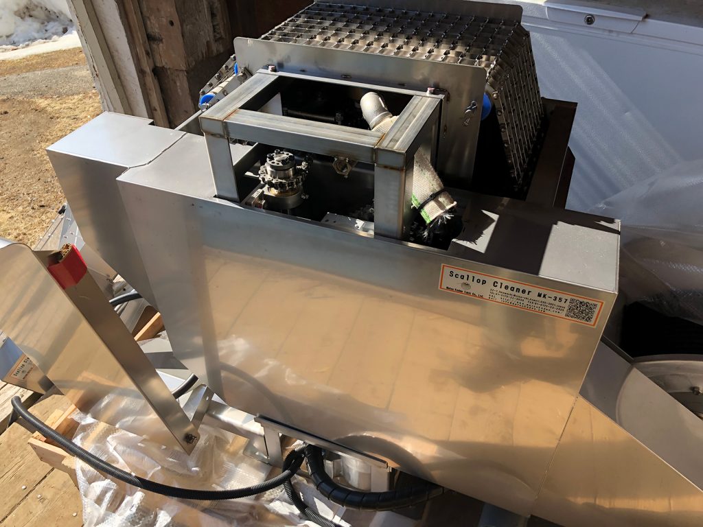 Metal washer washes scallops while on a dock