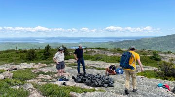 Several people on the summit of a mountain uder a blue clear sky